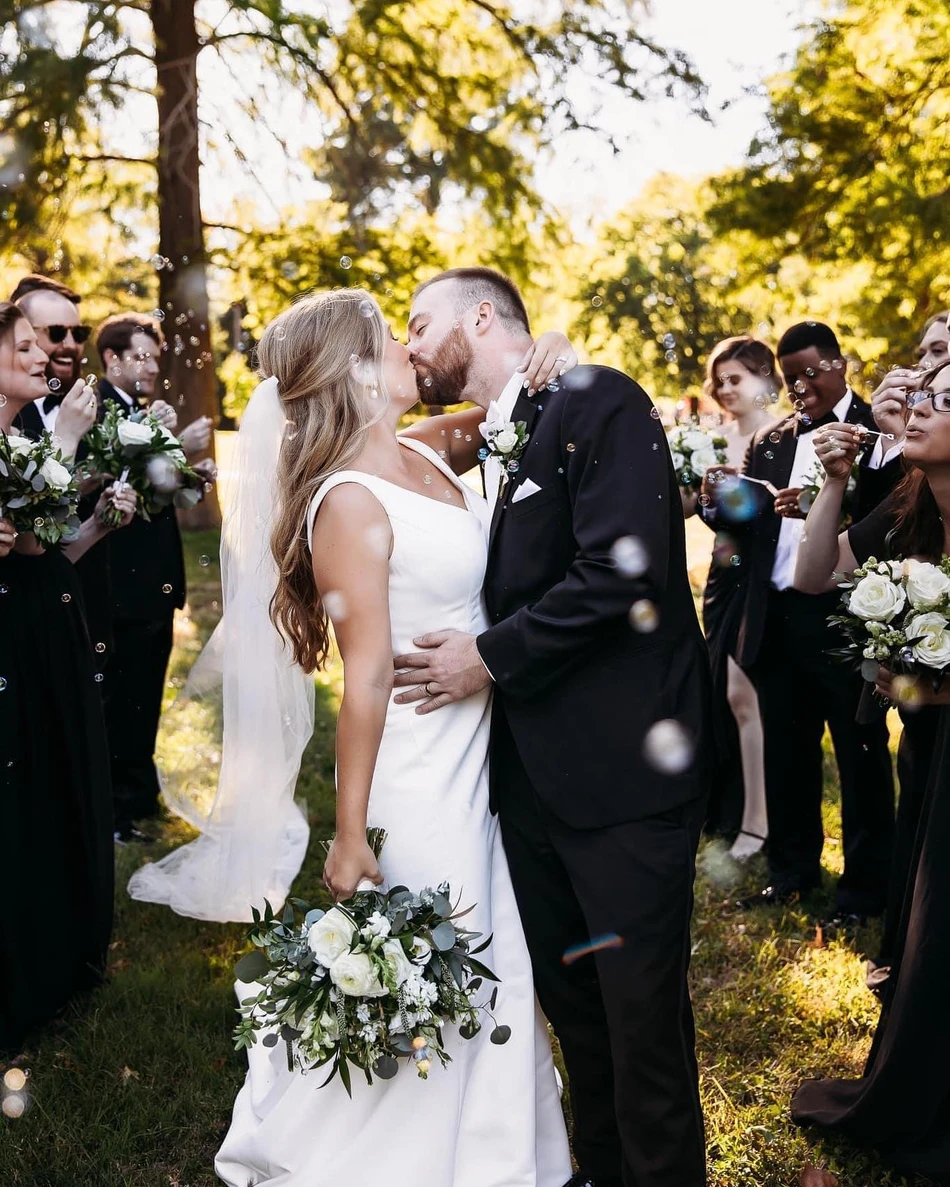 Newlyweds kiss beneath a shower of bubbles blown by their wedding guests.