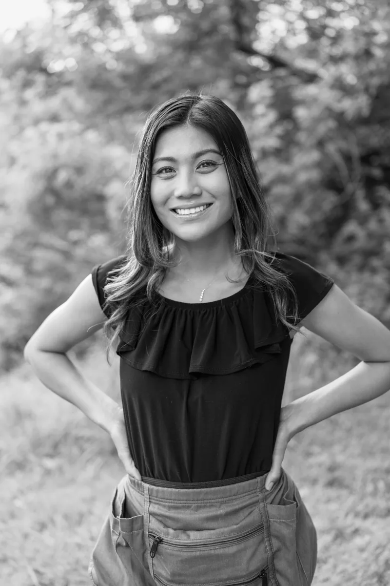 Klea Klingsick, wedding coordinator, standing confidently outdoors in a black-and-white portrait.
